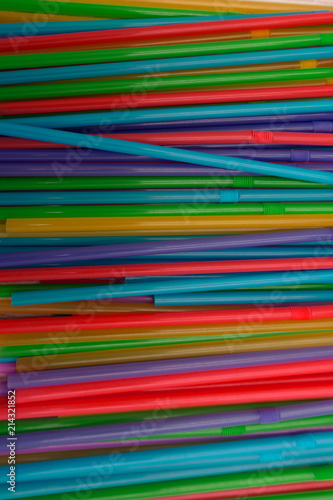 A lot of bright straws for a cocktail are scattered on the table . photo