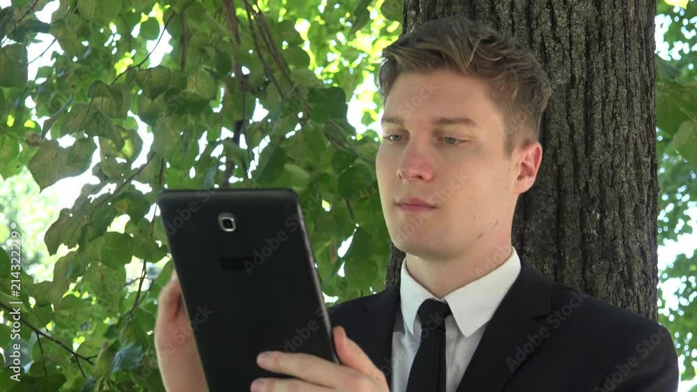 Close up handsome executive young business man leaning park tree with tablet 4K Close up handsome executive young business man leaning park tree with tablet 4K