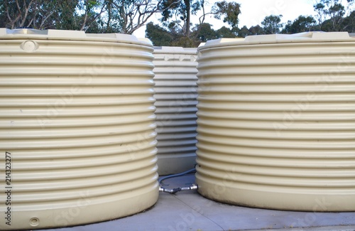 Set of three outdoor rainwater tanks on a farm in Australia with white corrugated sheeting sides