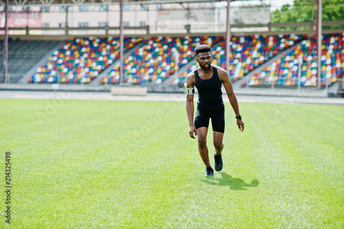 African american male athlete in sportswear doing jump exercise at stadium.