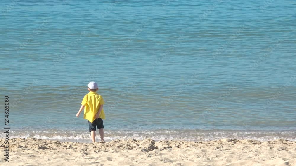 Happy child running on seashore, kid playing with sea waves Happy child running on seashore, kid playing with sea waves