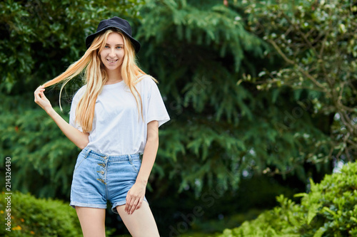 Young girl stands against green trees background