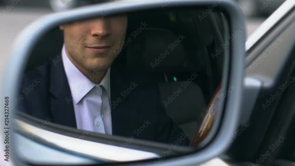 Successful businessman sitting in car and looking in side view mirror, driver Successful businessman sitting in car and looking in side view mirror, driver