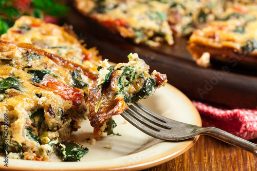 Portion of frittata made of eggs, mushrooms and spinach photo