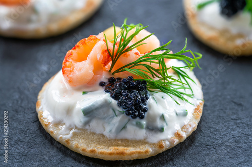 Cocktail blinis with crayfish, caviar and sour cream - gourmet party food. photo