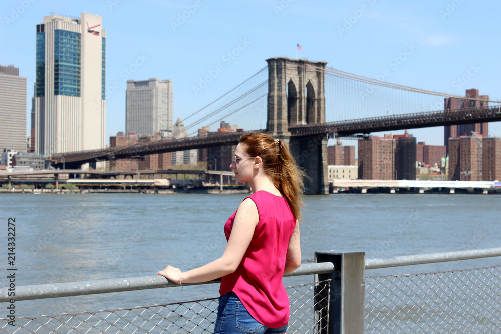 Junge Frau mit Blick auf die New Yorker Skyline und Brooklyn Bridge