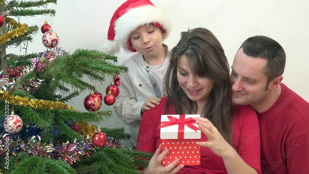 Happy family looking surprised at gift box close Christmas tree, playful child Happy family looking surprised at gift box close Christmas tree, playful child
