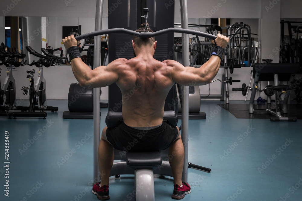 Hombre fuerte con grandes músculos entrenando jalón en el gimnasio. Ponerse en forma. Hombre fuerte con grandes músculos entrenando jalón en el gimnasio. Ponerse en forma.