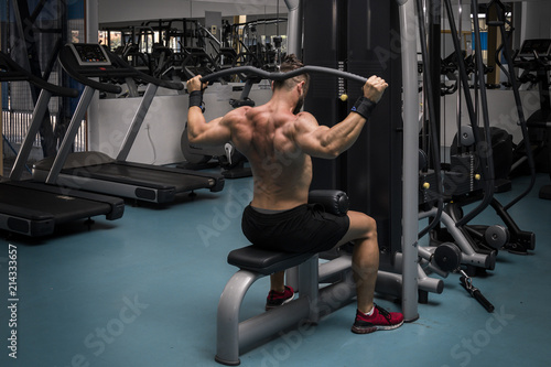 Hombre fuerte con grandes músculos entrenando jalón en el gimnasio. Ponerse en forma.