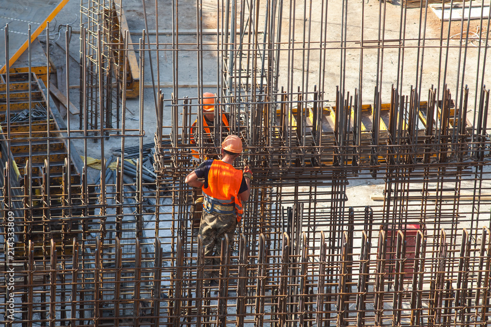 Fototapeta premium Construction of a large commercial building. Worker connects the armature at the construction site