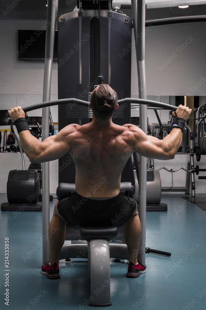 Hombre fuerte con grandes músculos entrenando jalón al pecho en el ...