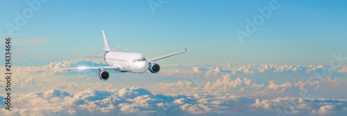 Passenger aircraft cloudscape with white airplane is flying in the evening sky cumulus clouds, panorama view.