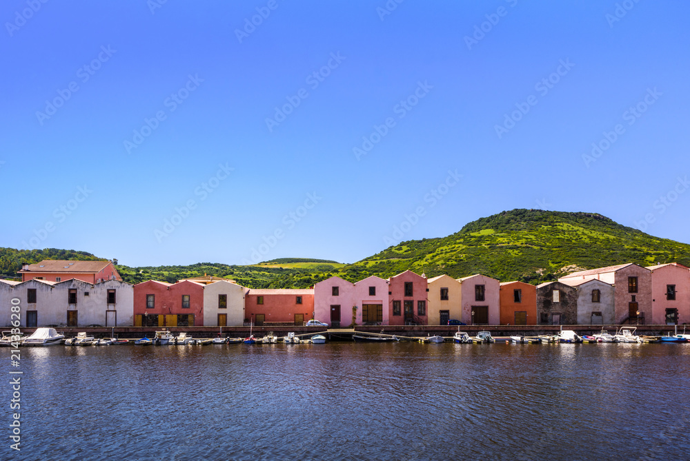 Colorful tannery houses on a canal with boats and green mountain range in the background, Bosa, Sardinia, Italy