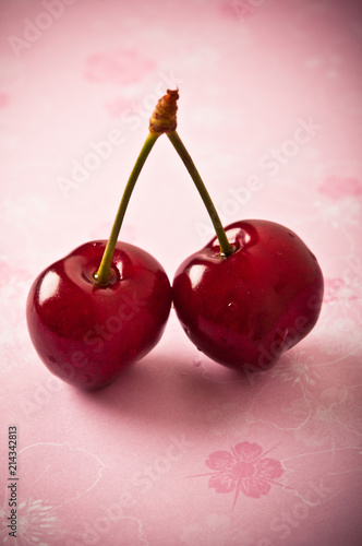 two cherries cherry over pink background with copy space 