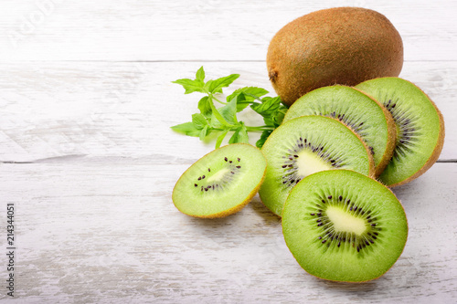Green kiwi and mint leaves on white wood background with space for text