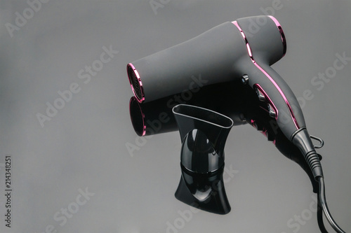 Grey mat hair dryer on the grey mirror background with copy space
