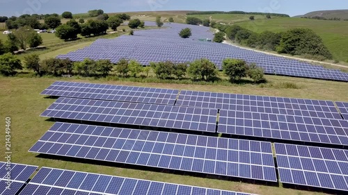 4k aerial drone view flying low over rows of solar panels at a solar power generation plant