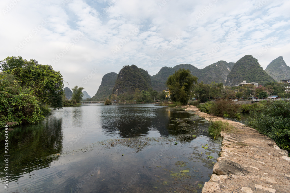 Panoramic view of green mountains reflected in still water. Yangshou, China Panoramic view of green mountains reflected in still water. Yangshou, China