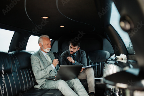 Fotografia Senior businessman and his assistant sitting in limousine and celebrating their job success