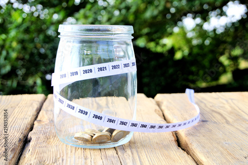 Coins in glass jar with calendar years wrapped round