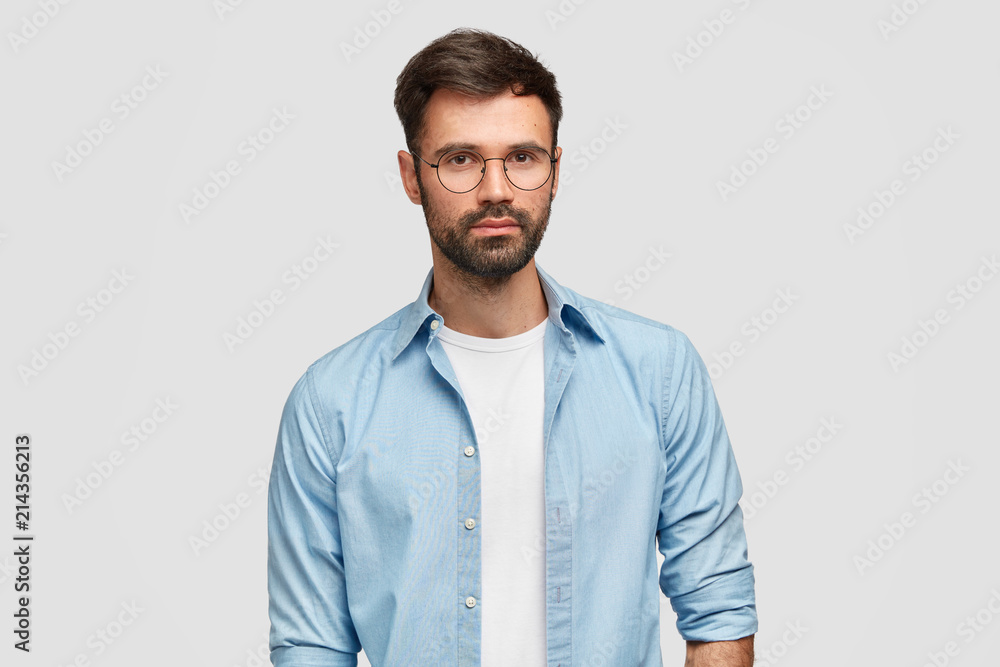 Horiozontal shot of handsome male freelancer with thick bristle, dressed in fashionable shirt, listens good proposal from colleague, analyzes information, isolated over white background. Masculinity Horiozontal shot of handsome male freelancer with thick bristle, dressed in fashionable shirt, listens good proposal from colleague, analyzes information, isolated over white background. Masculinity