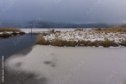 Fototapeta Naklejka Na Ścianę i Meble -  Scenic View Of Frozen Lake Against Foggy Mountains