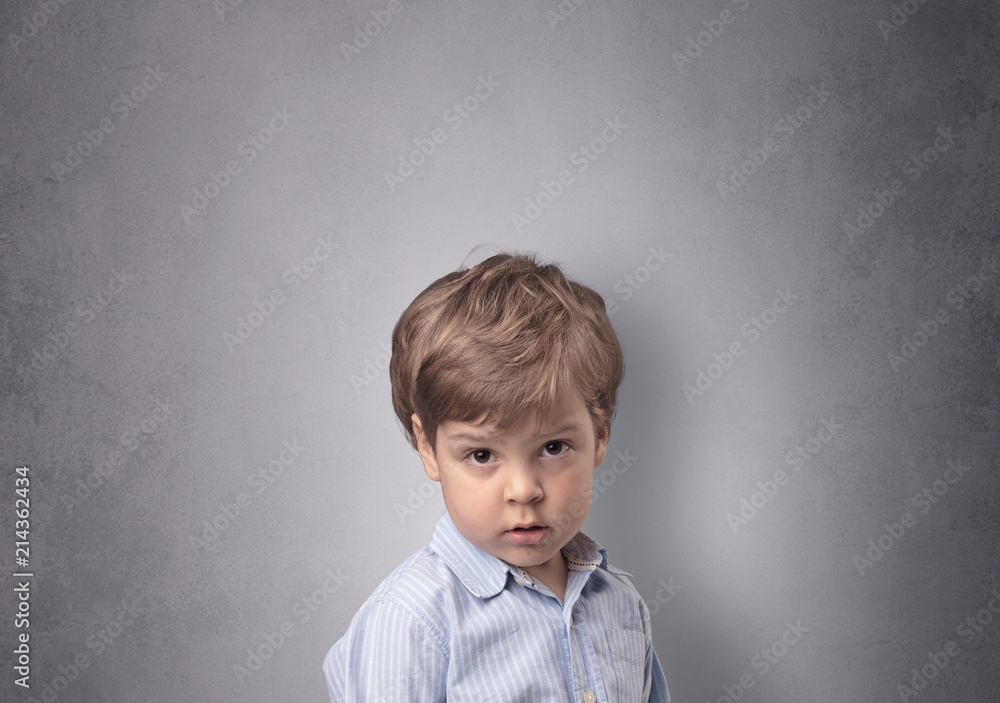 Fototapeta premium Adorable little boy portrait with empty grey wall background