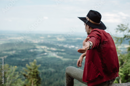 Man traveler sitting on a stone on the background of nature