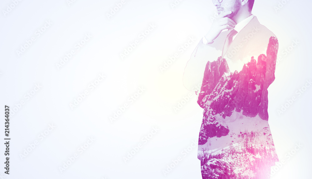 Young businessman in suit standing with sunny snowy mountain and trees graphic. Young businessman in suit standing with sunny snowy mountain and trees graphic.