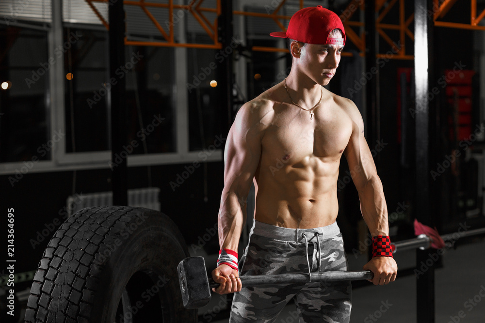 Muscular asian man with sledge hammer near big wheel tires in gym. Equipment  for crossfit training Stock Photo | Adobe Stock