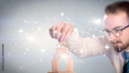Young handsome businessman using wooden building blocks with interconnected lines and dots around him