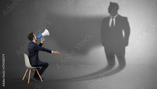 Photography Humble businessman staying and offering stuffs to a huge businessman shadow