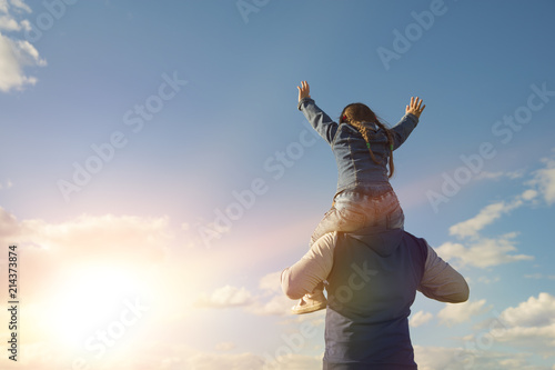 the child is on his father's shoulders. Dad and child daughter playing together outdoors on sunset background. father's day.