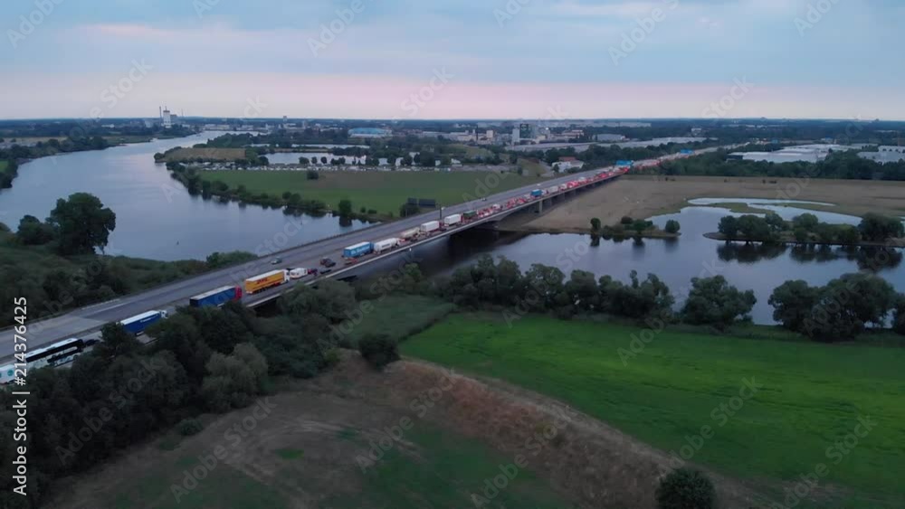 Autobahnbrücke bei Morgendämmerung über Fluss mit Stadt im Hintergrund Autobahnbrücke bei Morgendämmerung über Fluss mit Stadt im Hintergrund