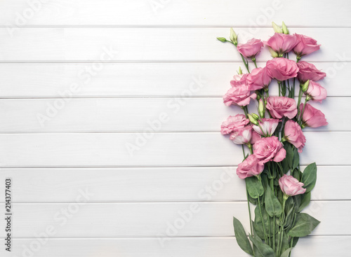 Beautiful pink eustoma flowers on white wooden background. Copy space, top view, © Irina Sokolovskaya