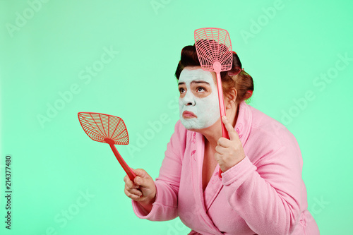 femme ronde et drôle avec bigoudis chassant les mouches avec tapette   photo