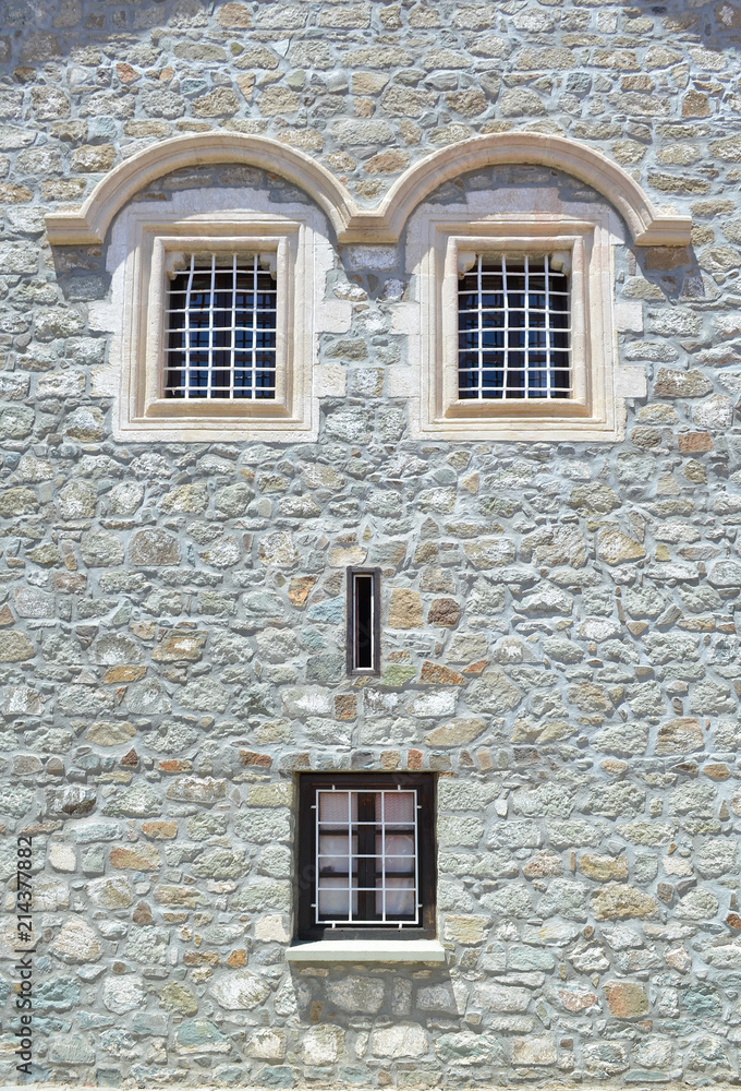 Window on a stone wall of the house. Due to the windows location, facade looks like a human face