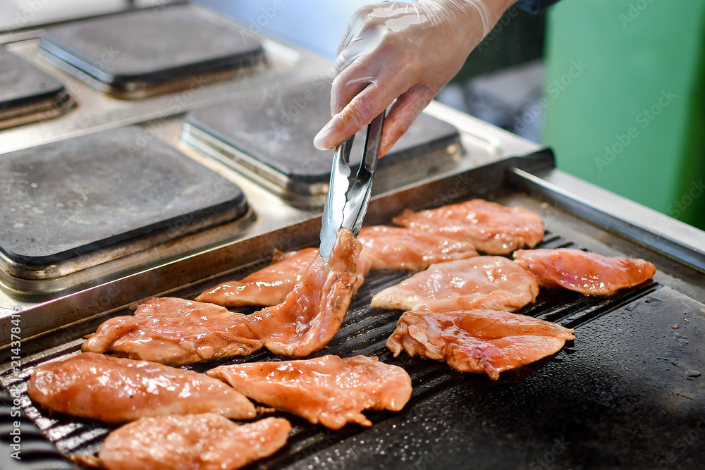 chicken fillet fried on the grill, the chef turns the fillet forceps chicken fillet fried on the grill, the chef turns the fillet forceps