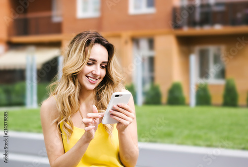 smiling girl with smartphone. Texting, chatting. Social media, communication people, photo, gadget addicted concept. Multistory house, building block on background