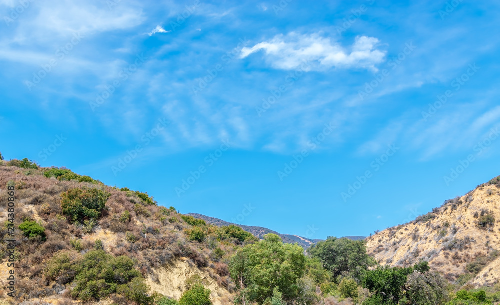 Blue sky and white clouds form a bowl in center of Southern California mountains on summer day