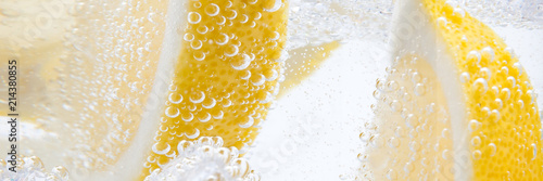 In a glass with cubes of melting ice slices of a juicy lemon.