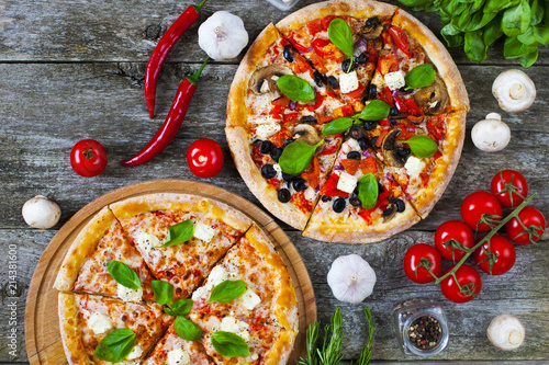 Homemade pizza with tomatoes, mozzarella and basil. Top view with copy space on wooden table.