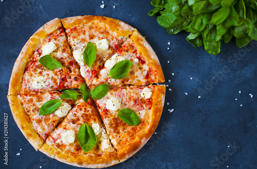 Homemade pizza with tomatoes, mozzarella and basil. Top view with copy space on dark stone table.