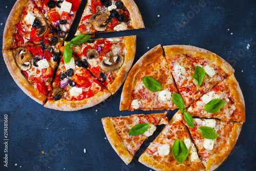 Homemade pizza with tomatoes, mozzarella and basil. Top view with copy space on dark stone table. photo