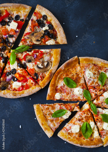 Homemade pizza with tomatoes, mozzarella and basil. Top view with copy space on dark stone table. photo