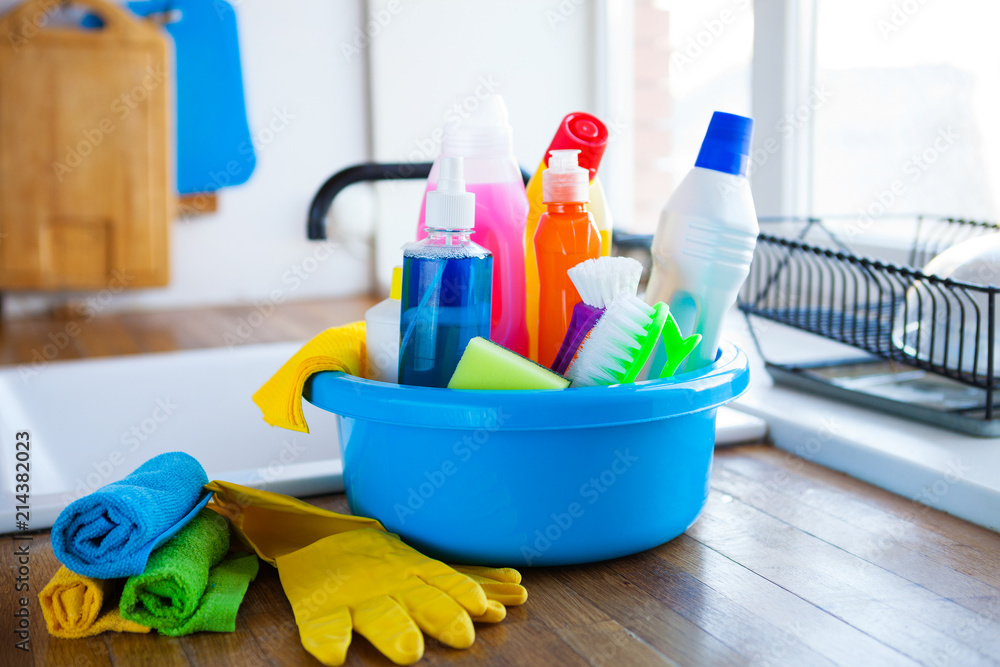 Basket with cleaning items on blurry background white citchen. Cleaning concept. Basket with cleaning items on blurry background white citchen. Cleaning concept.