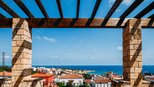 Frame of coastline of Costa Dorada in Miracle Beach. Sea, beach, palms and tiled roofs of houses at Tarragona, Catalonia, Spain photo