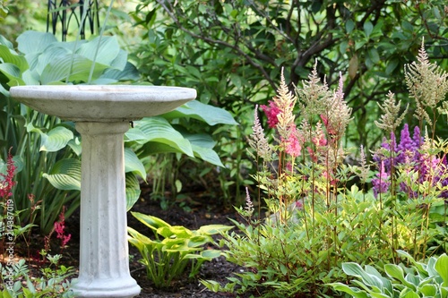 Schilderij op canvas Stone bird bath in flower garden