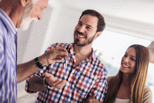 Real estate agent giving keys to couple of customers