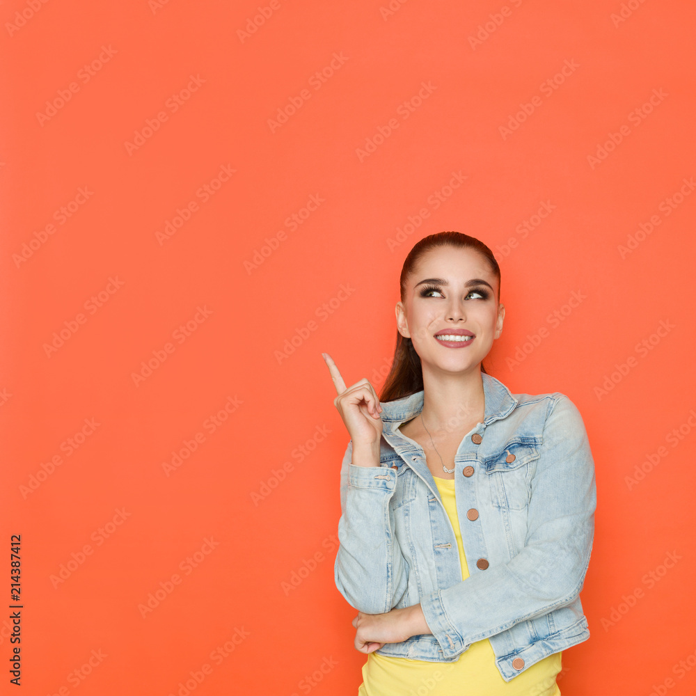 Beautiful Woman In Jeans Jacket Is Pointing Up And Looking Away Beautiful Woman In Jeans Jacket Is Pointing Up And Looking Away